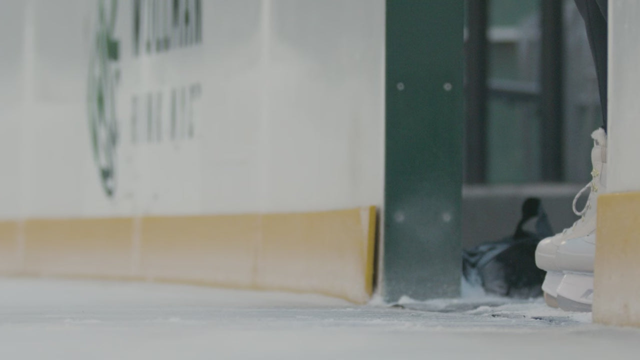 close up on a pair of white ice skates gliding out onto the ice