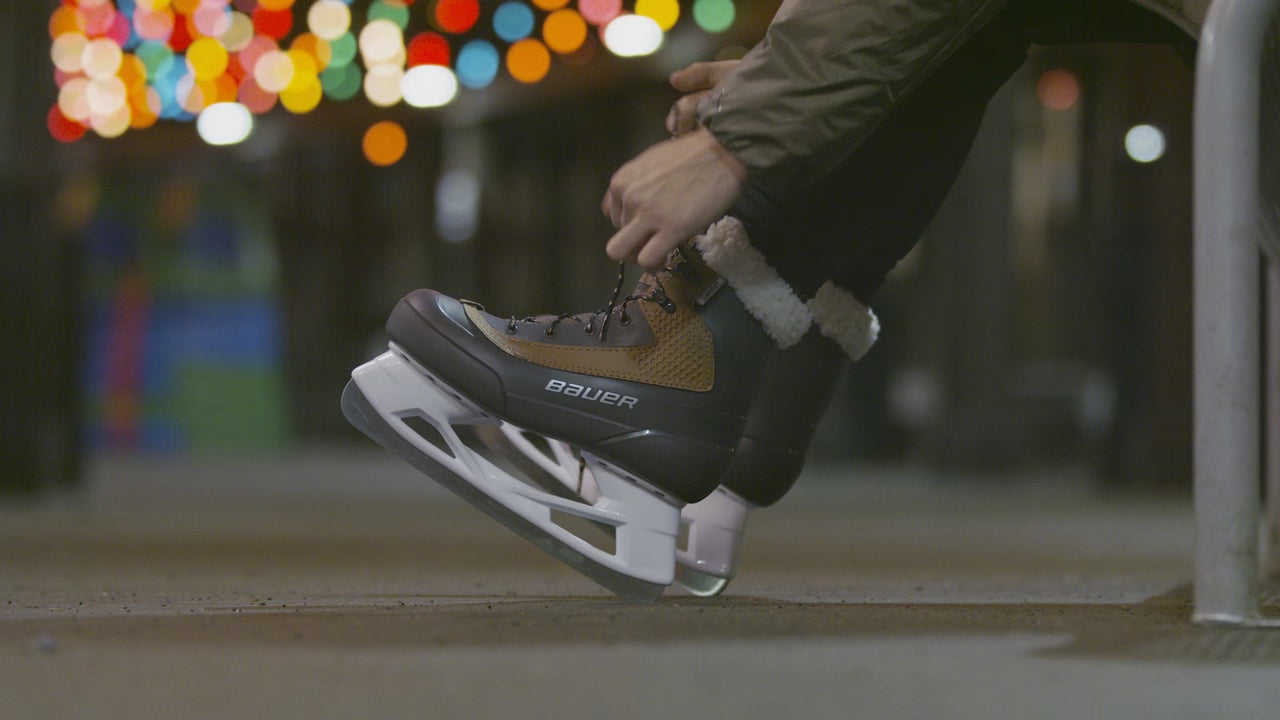 lacing up Bauer Whistler skates next to an outdoor ice rink in NYC